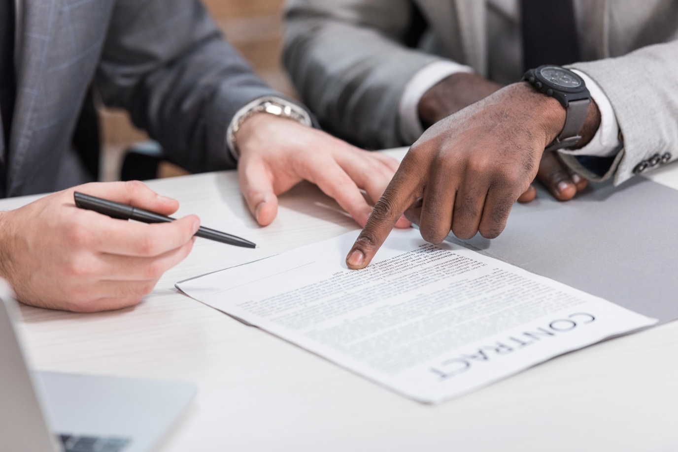 Cropped view of multiethnic business partners signing contract on office table